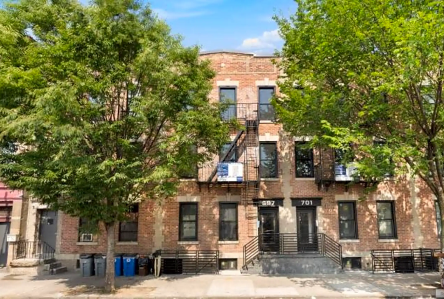 a brick apartment building with trees in front of it
