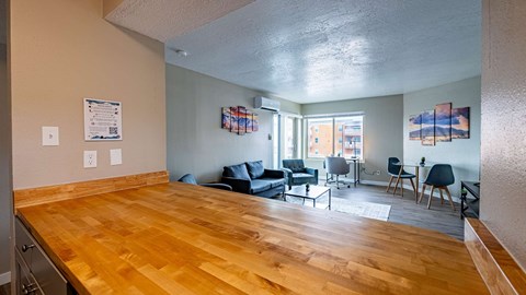 A living room with a wooden floor and a dining table with chairs.