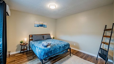 A bedroom with a bed, nightstand, and a ladder.
