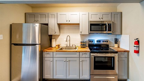 A modern kitchen with a stainless steel refrigerator, oven, and cabinets.