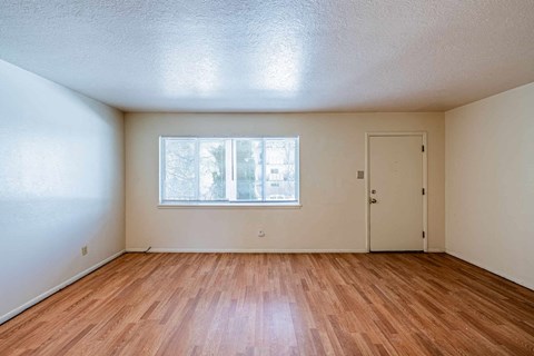 A room with wooden floors and a window with blinds.