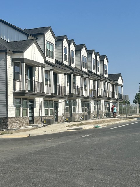 A row of townhouses with a person standing in front of the first one.