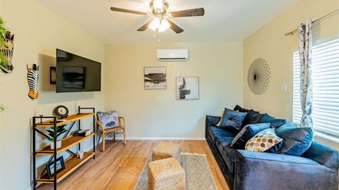 A living room with a blue couch and a ceiling fan.