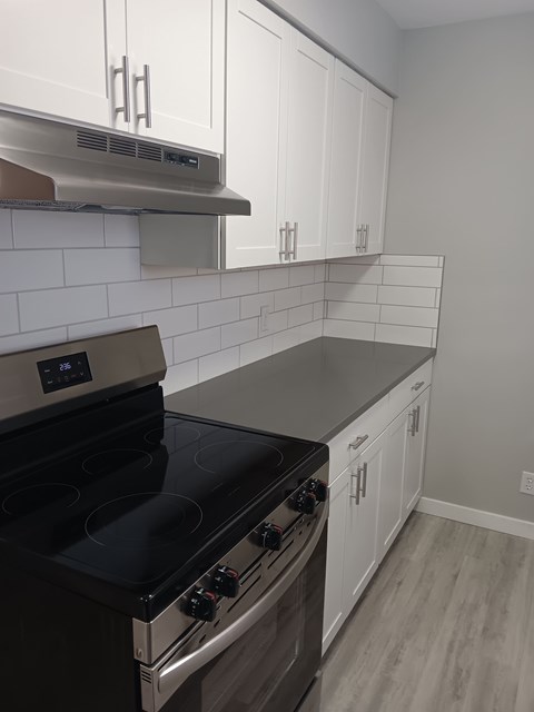 A modern kitchen with a stove top oven and white cabinets.
