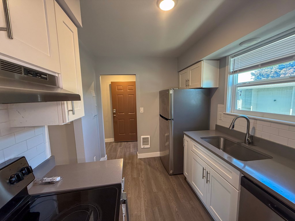 A kitchen with a stove, refrigerator, and sink.