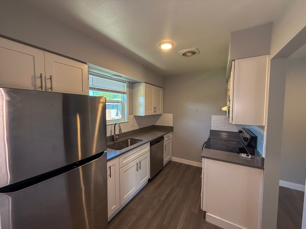 A kitchen with a stainless steel refrigerator and white cabinets.