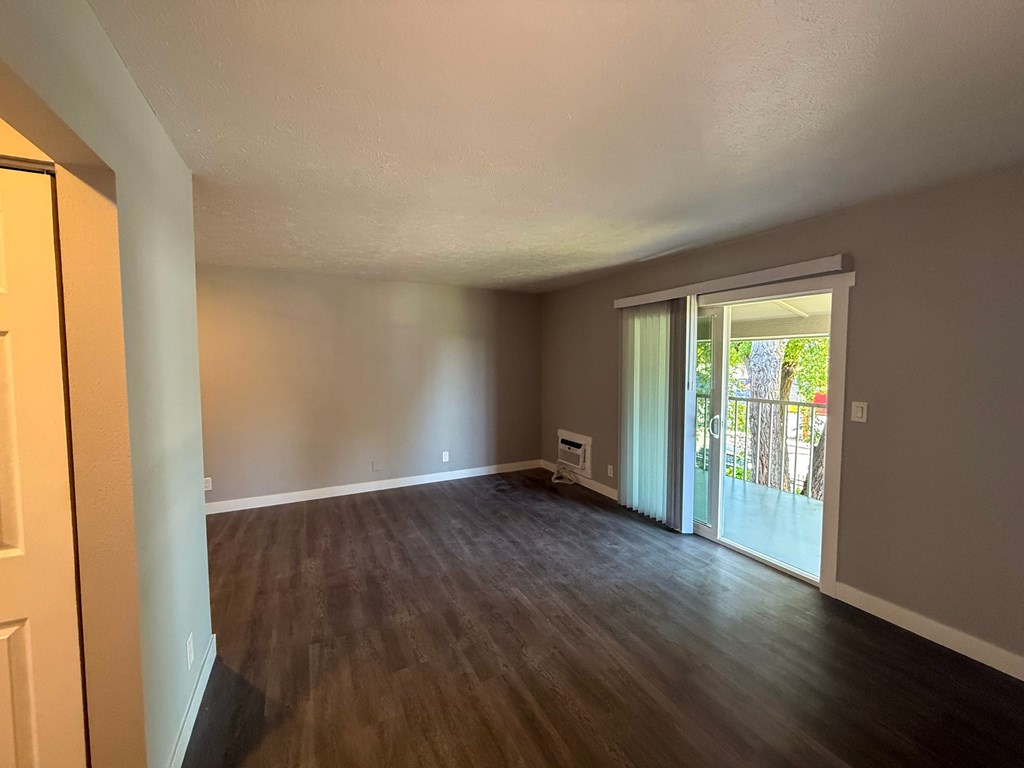 A room with wooden flooring and a sliding glass door leading outside.