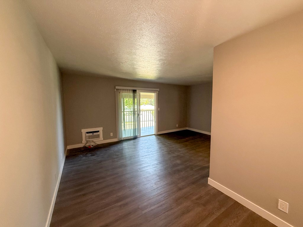 A room with wooden flooring and a window with blinds.