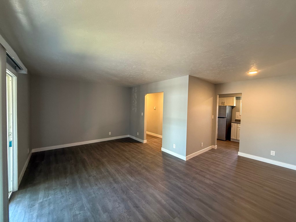 Empty room with wooden flooring and white walls.