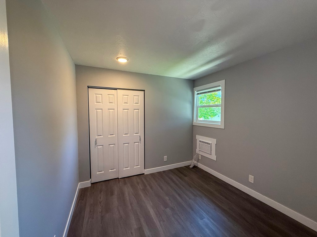 A room with a white door and a window showing greenery outside.