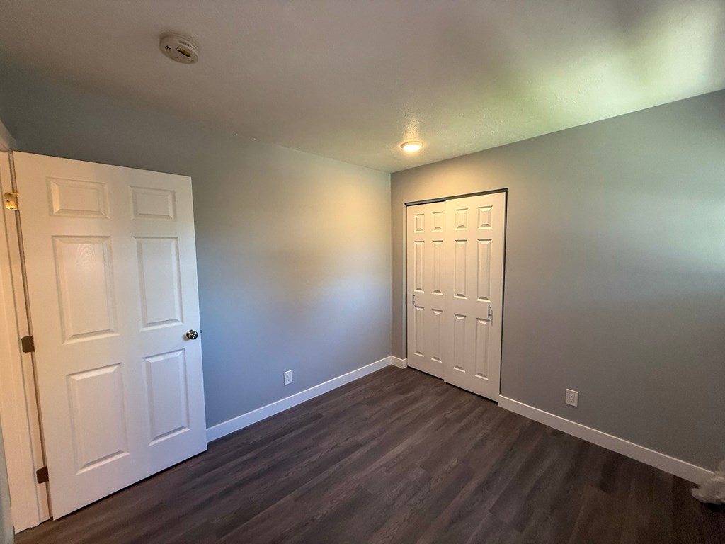 A room with two white doors and wooden floors.