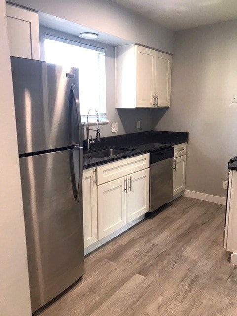 A kitchen with a stainless steel refrigerator and white cabinets.