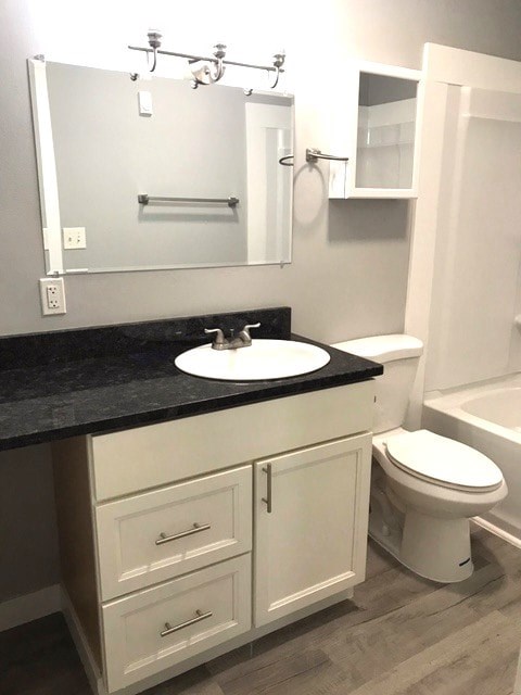 A white bathroom with a black counter top and a white toilet.