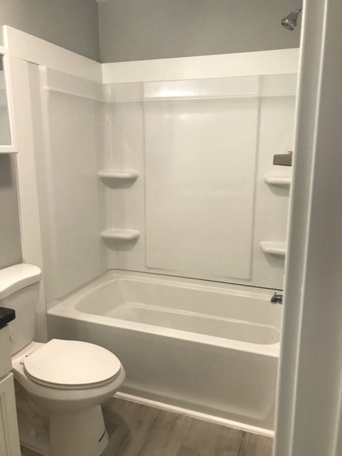 A white toilet sits next to a white bathtub in a bathroom.