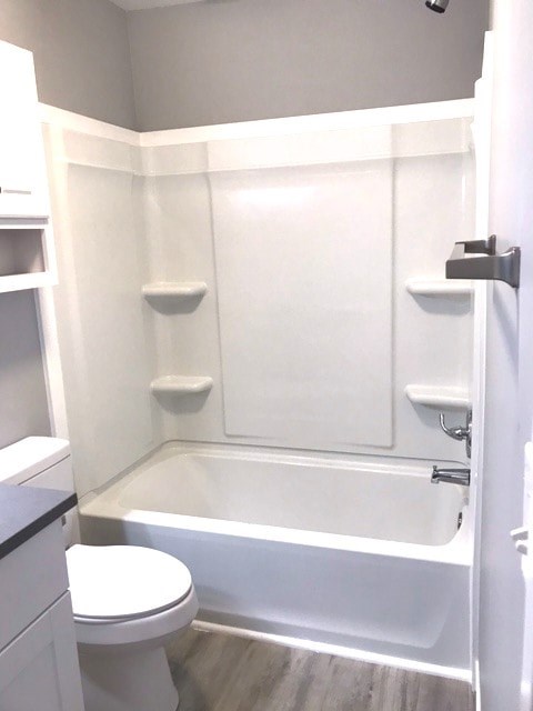 A white toilet sits next to a bathtub in a small bathroom.