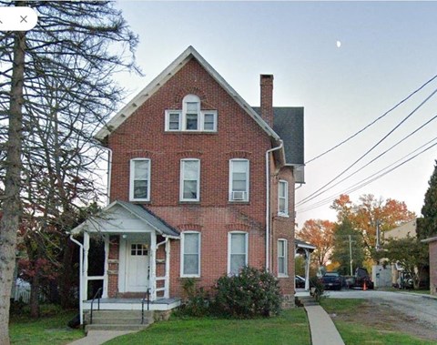 A red brick house with a white door and windows.