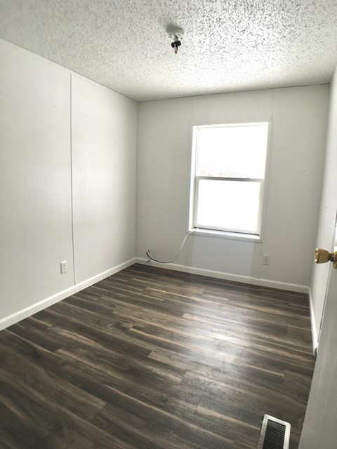 an empty room with wood floors and a window