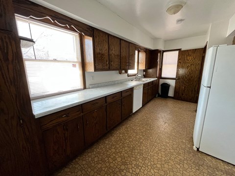 an empty kitchen with a refrigerator and a window
