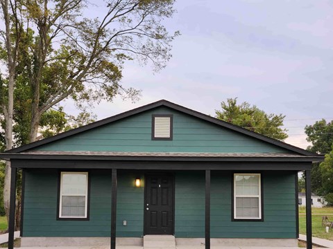 the front of a green house with a black door