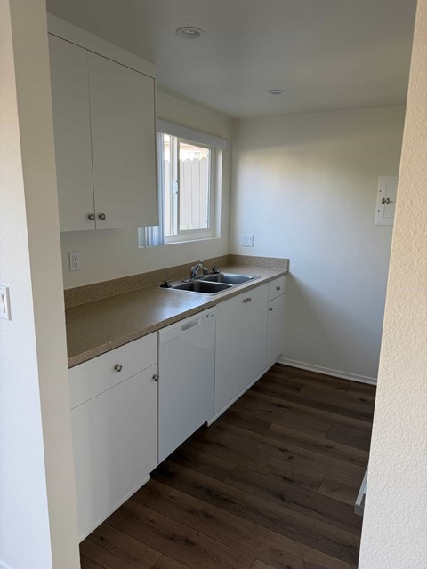 A kitchen with white cabinets and a wooden floor.