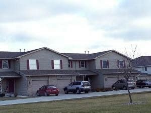 A house with a grey roof and a red car parked in front.