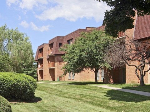 a brick building with grass and trees in front of it