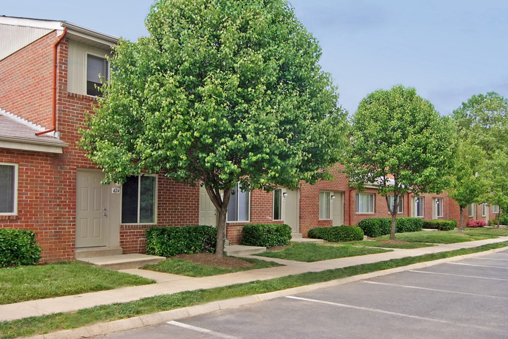 a row of brick apartment buildings with trees and sidewalks