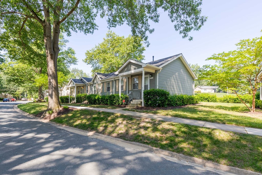 A tree-lined street with a house on the corner.