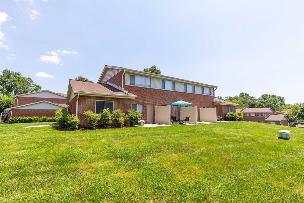 A house with a red brick exterior and a green lawn.