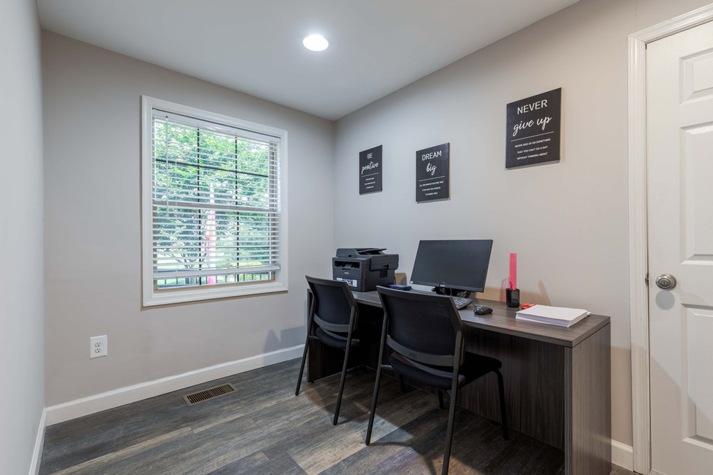 A room with a desk, chairs, and inspirational quotes on the wall.