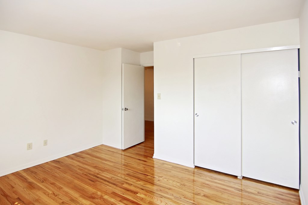 an empty room with wood floors and white closets