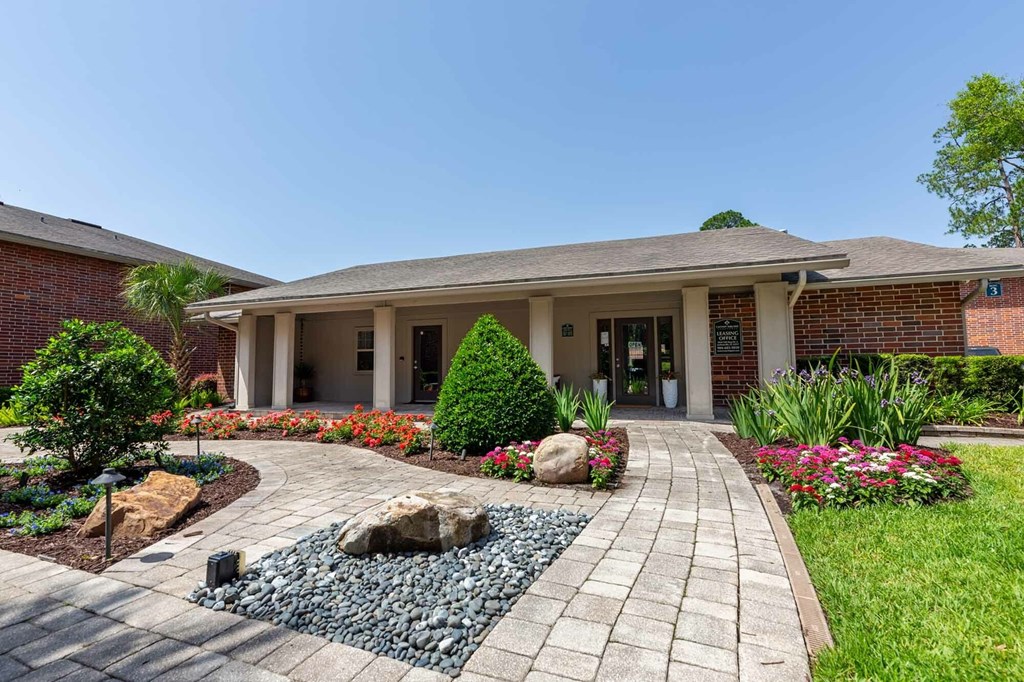 A building with a brick facade and a landscaped front yard.