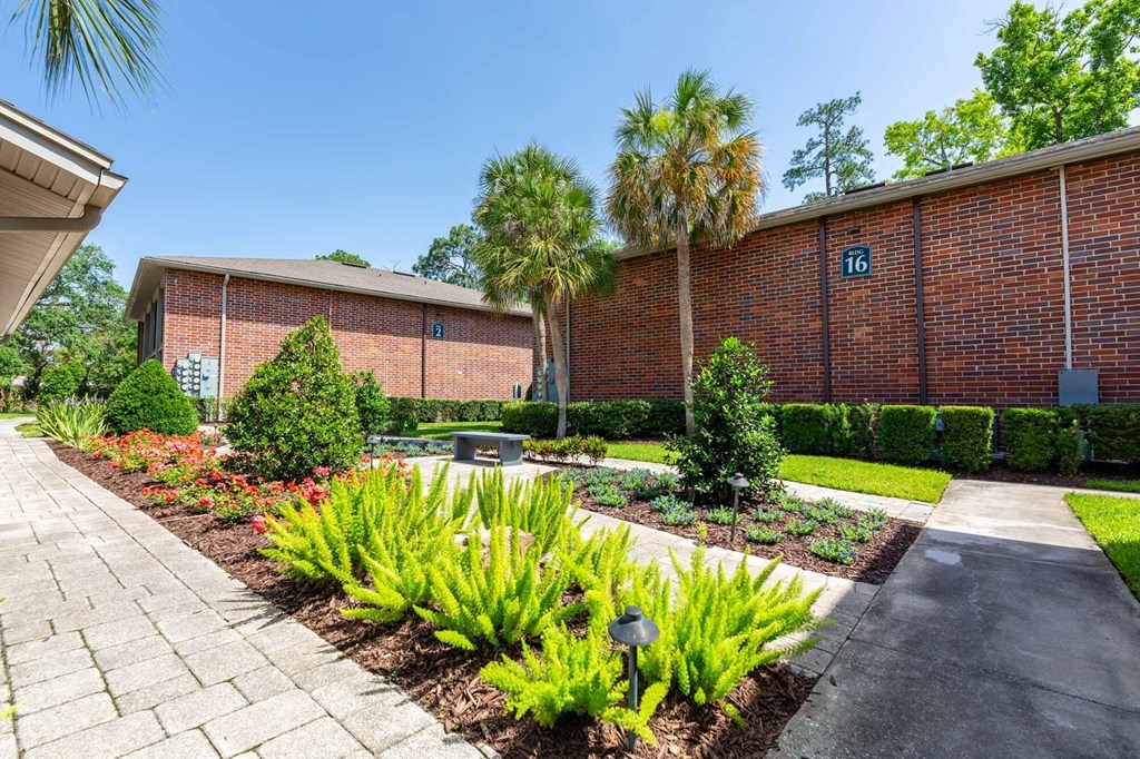 A brick building with the number 16 on it is surrounded by greenery.