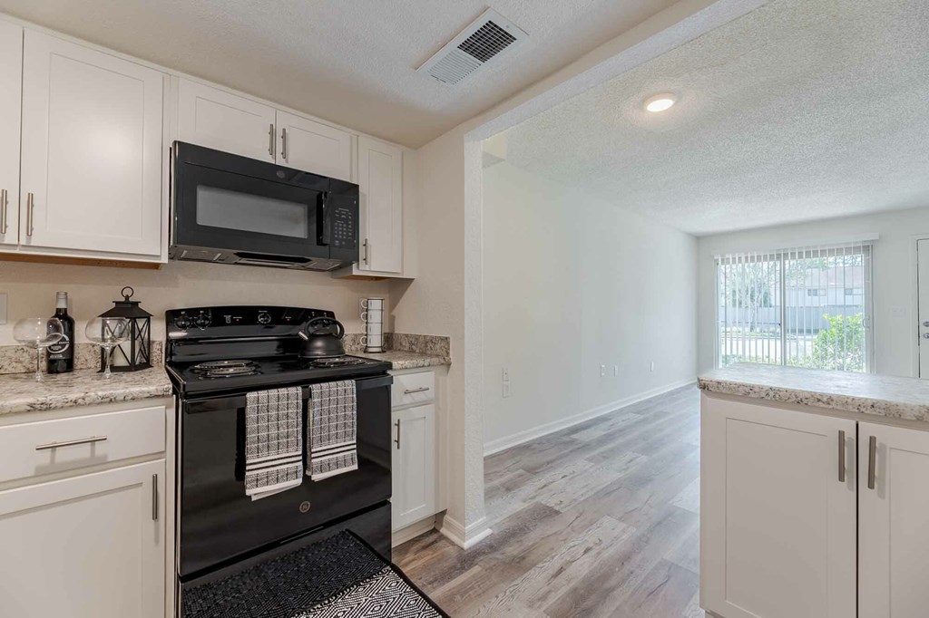 A kitchen with a black stove top oven and white cabinets.