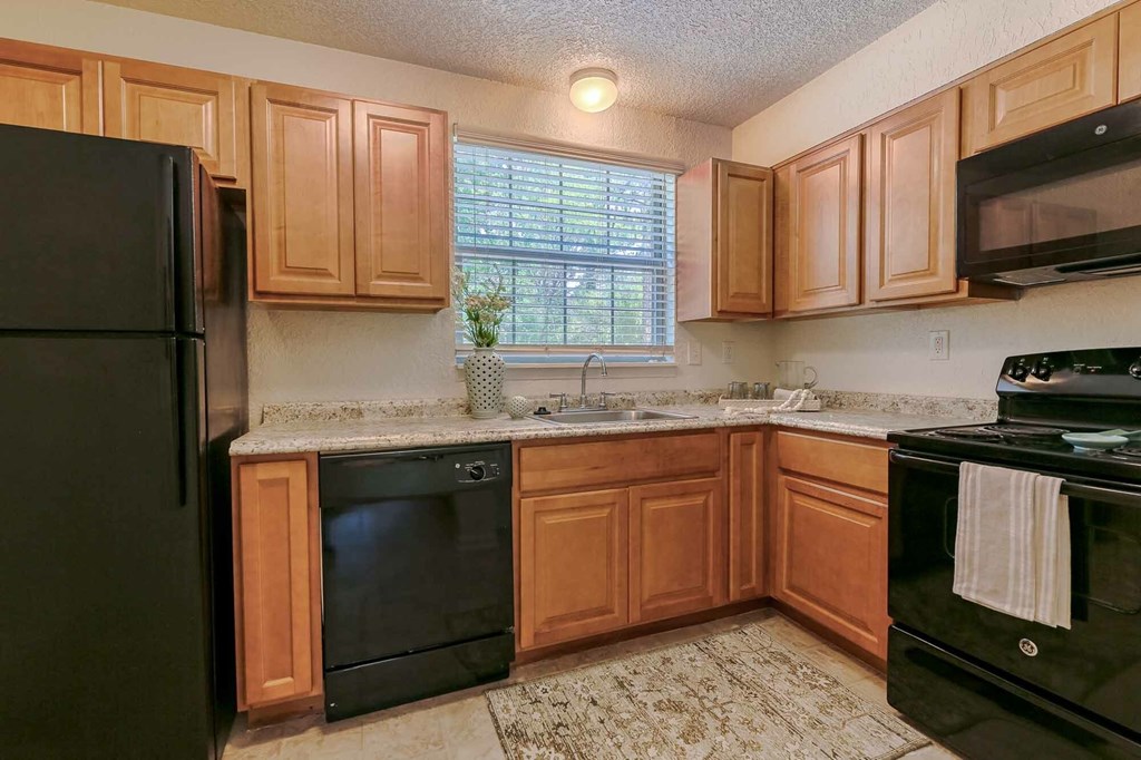 A kitchen with black appliances and wooden cabinets.