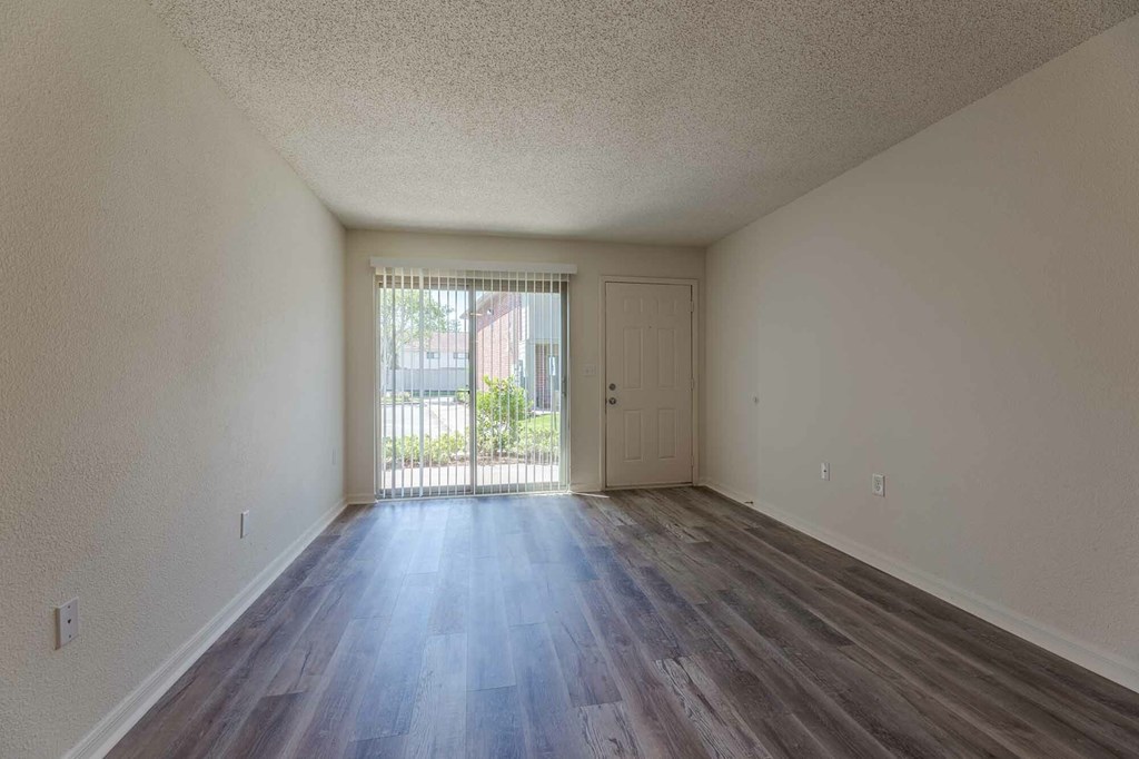 A room with a wooden floor and a door leading outside.