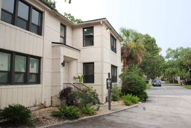 A two-story beige house with a black gate in front.