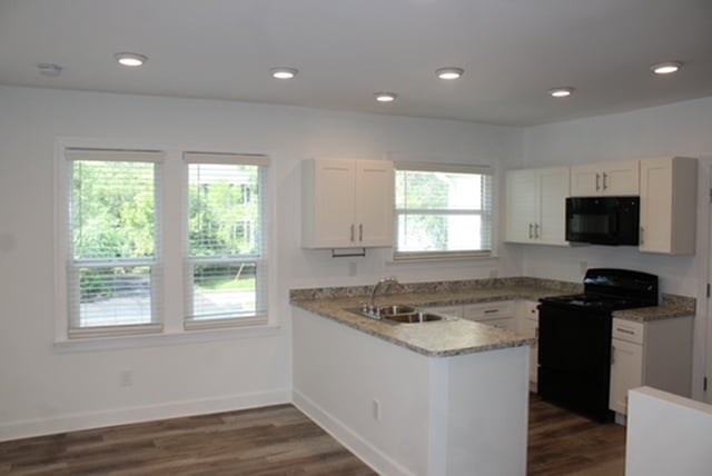 A kitchen with black appliances and white cabinets.
