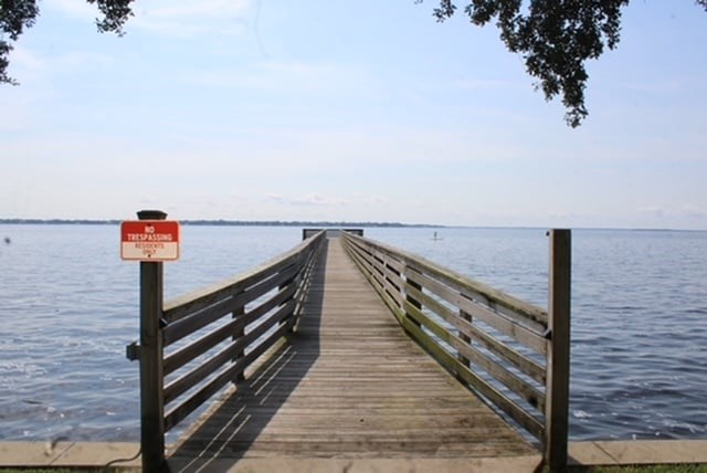 A wooden pier extends into the water with a sign on it.