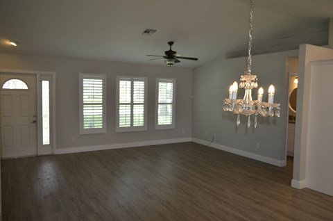 an empty living room with a ceiling fan and a chandelier