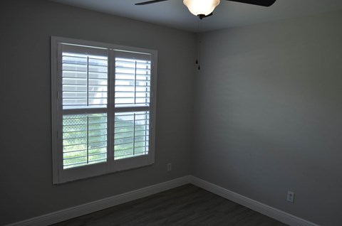 an empty room with a window and a ceiling fan