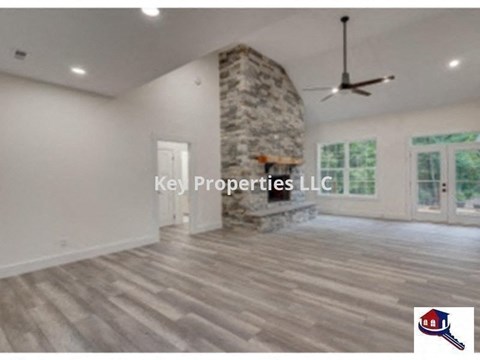 A spacious room with a stone fireplace and Key Properties LLC logo.