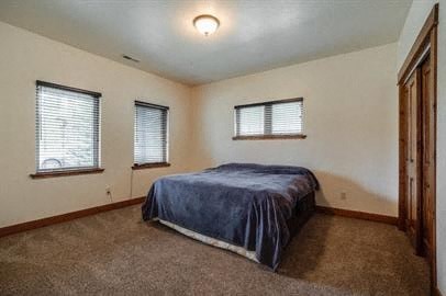 a bedroom with a bed and three windows