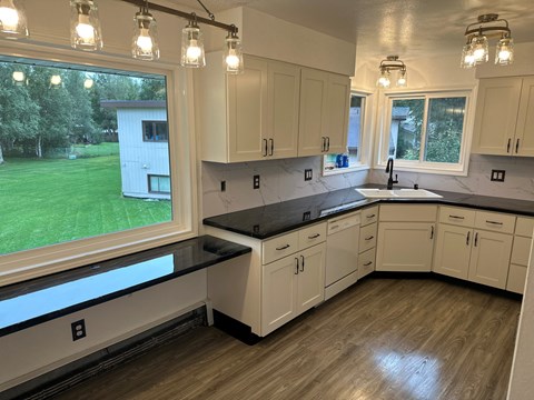 A kitchen with white cabinets and a black countertop.