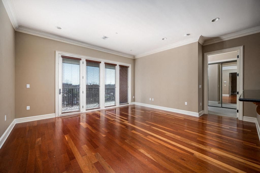 A room with wooden floors and a glass door leading to a balcony.