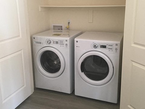 Two white front loading washing machines in a small laundry room.