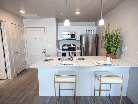 A kitchen with a white counter and two gold chairs.