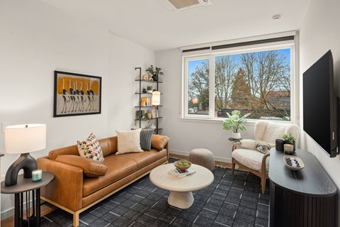 A living room with a brown couch, a white coffee table, and a painting on the wall.