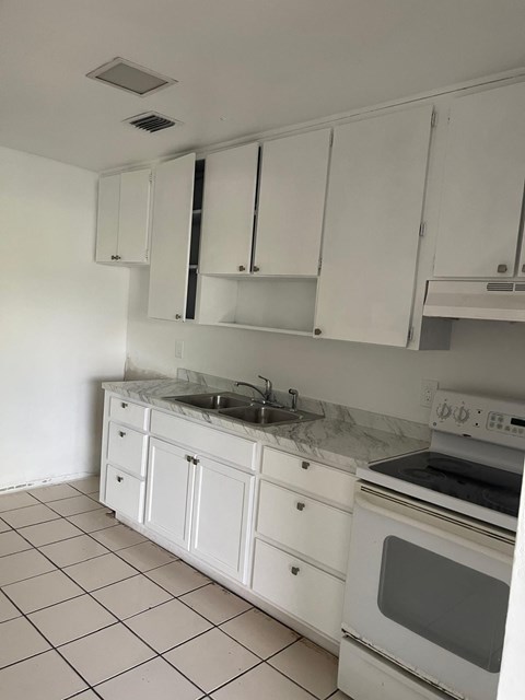 A kitchen with white cabinets and appliances.