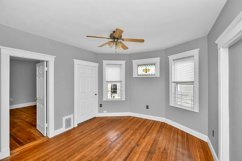 a living room with wood floors and a ceiling fan